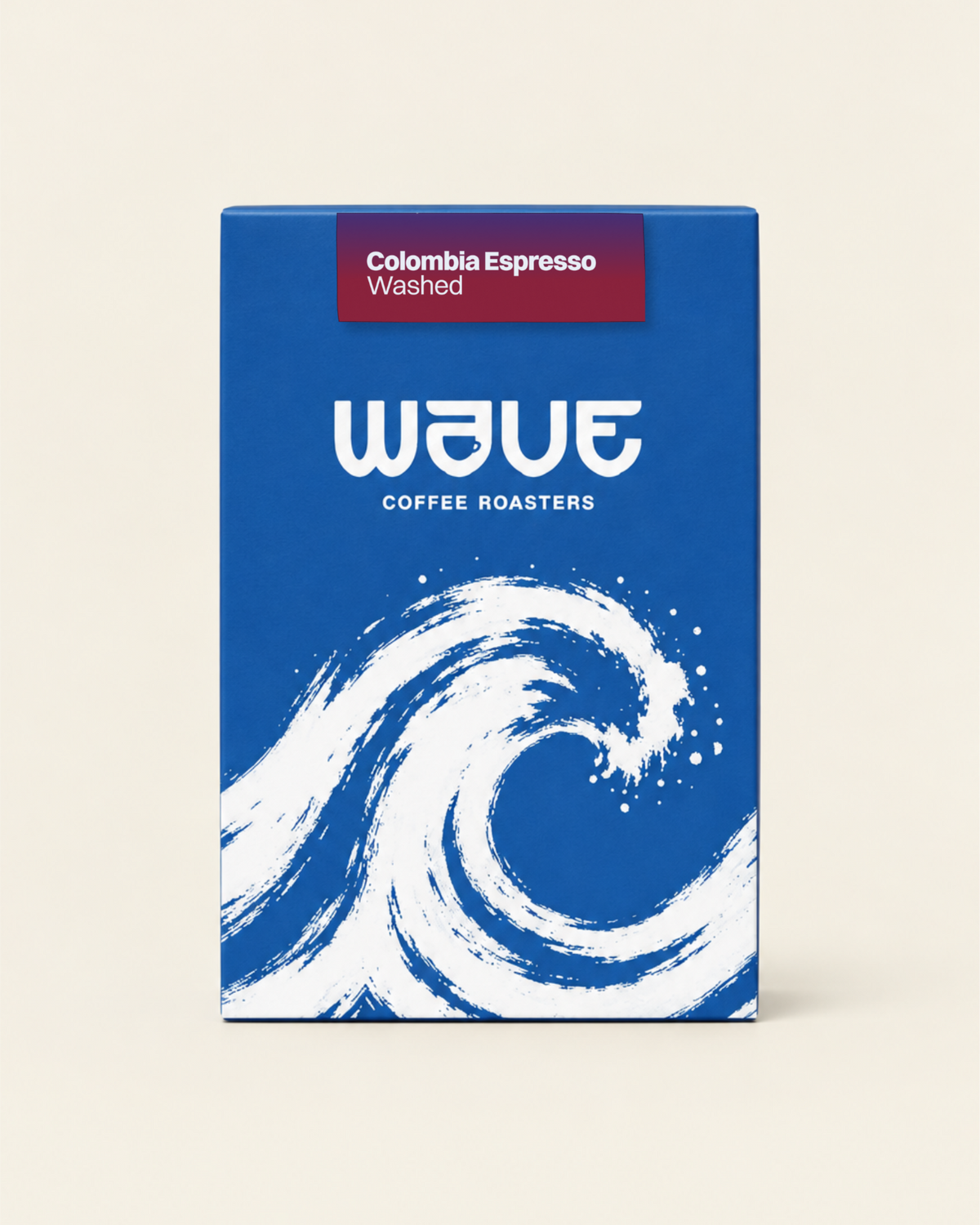 A rectangular coffee roaster box standing upright on a light beige background. The box has a blue or a dark blue design with a large white wave illustration and the visible brand name 'wave coffee roasters' with specialty coffee label: 'Colombia Espresso Washed'