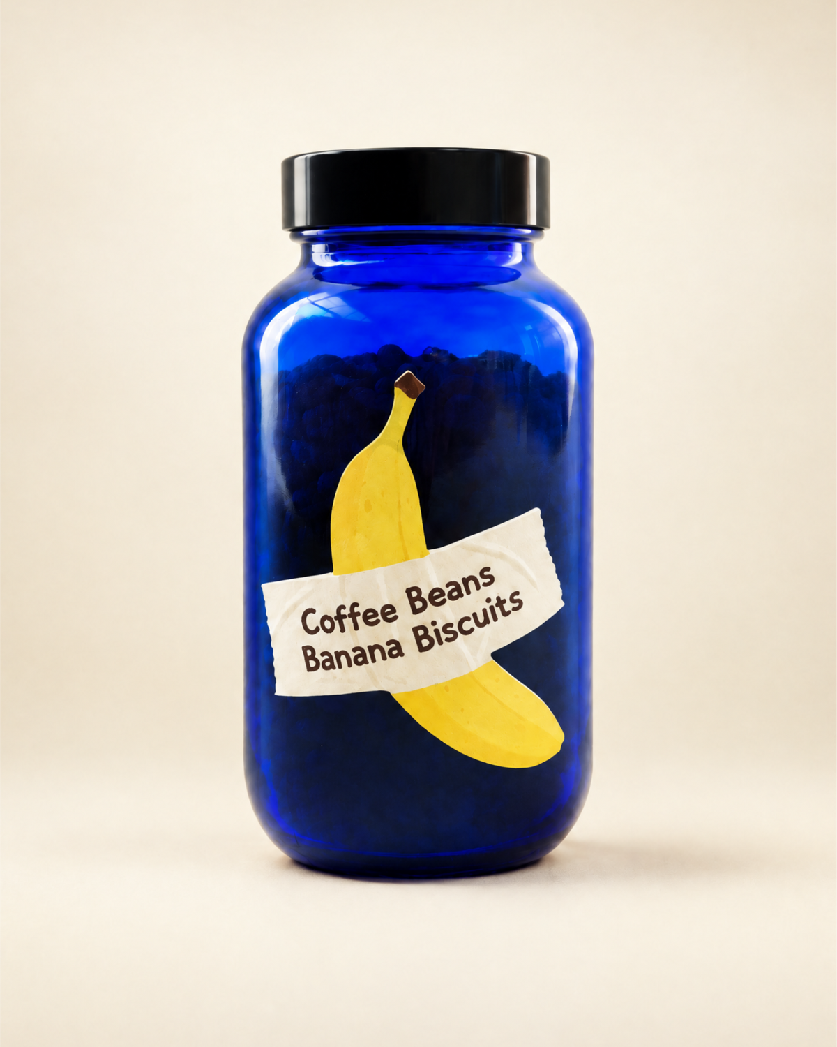 A cobalt blue glass jar with a black screw-on lid, featuring a printed label of a yellow banana and the text specialty coffee label 'Coffee Beans Banana Biscuits'.