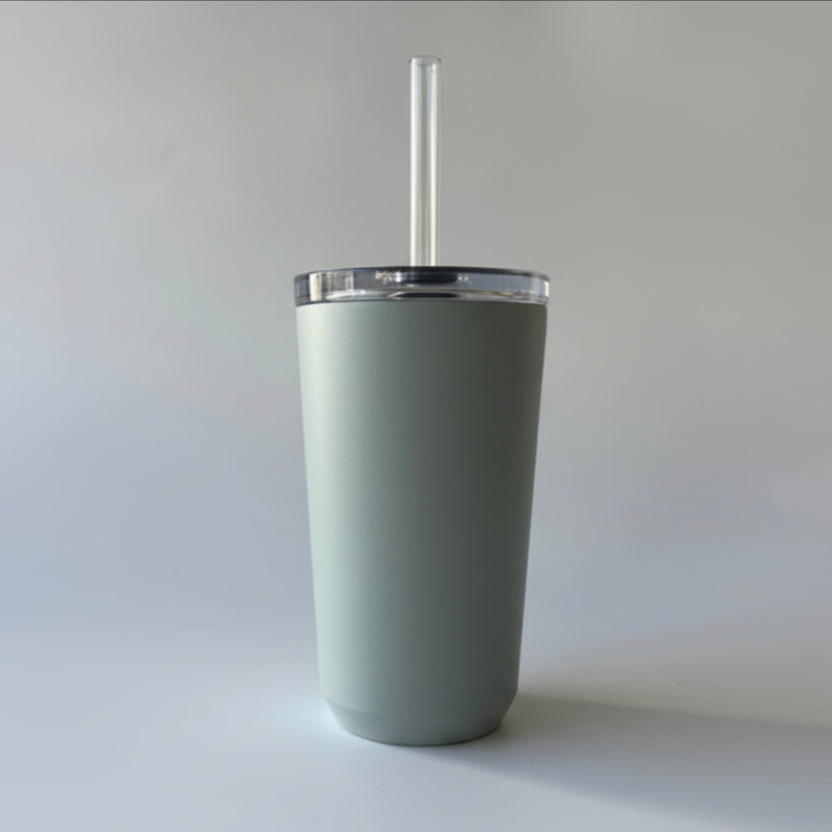 Gray tumbler with a straw and brown label on a light gray background