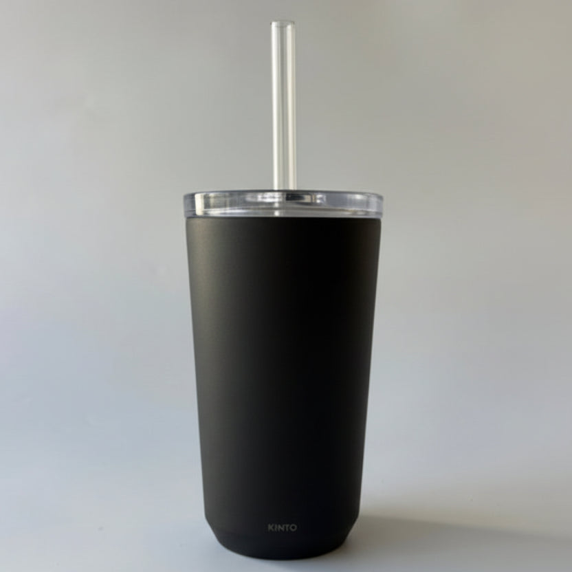 Black tumbler with a straw and brown label on a white background