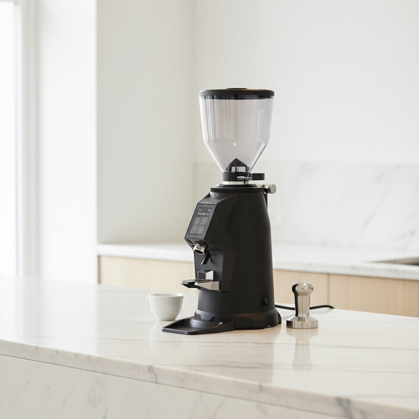 A black and dark gray coffee grinder with a clear hopper on a white background.