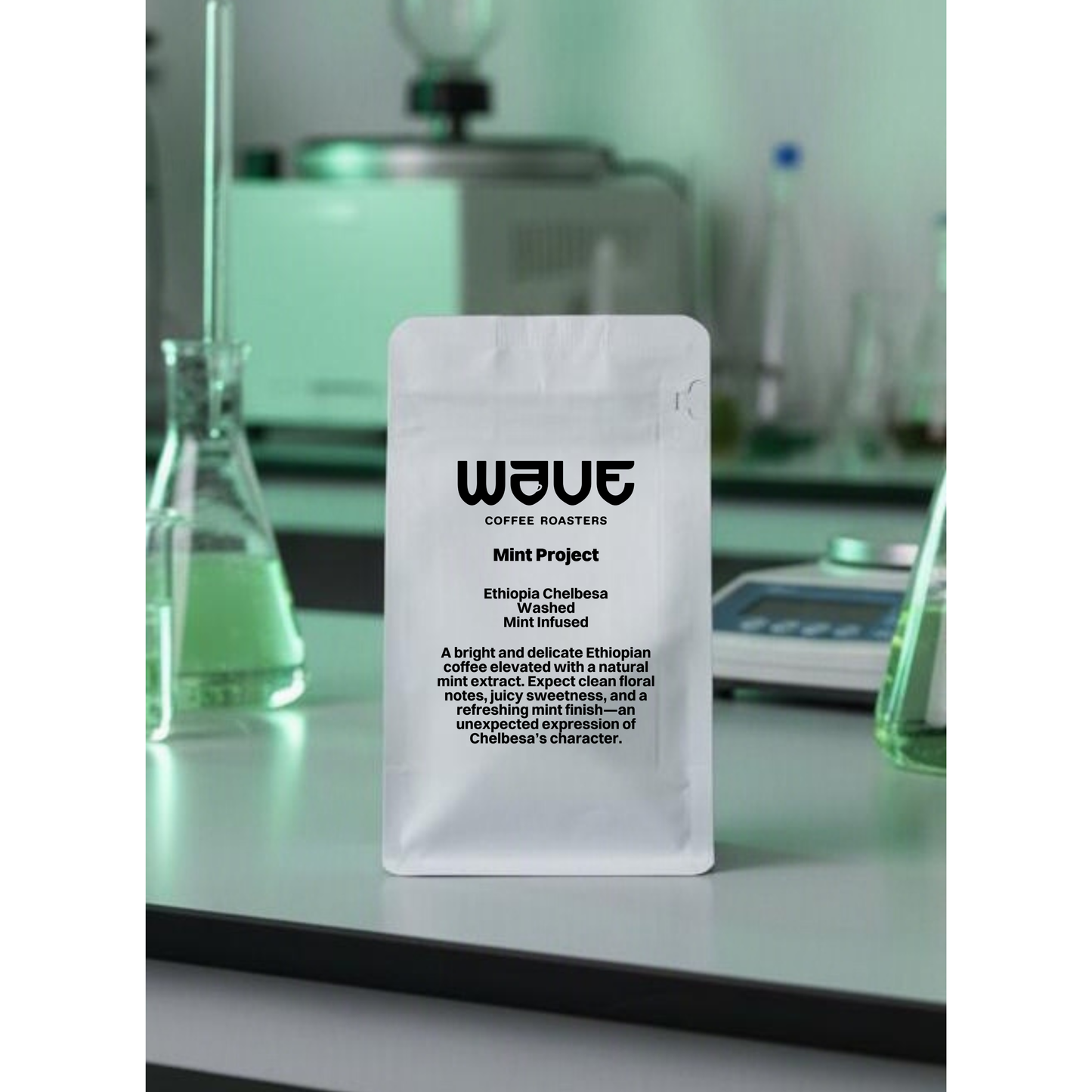 A white stand-up coffee bag with a hanging hole and a large white label reading WAVE Coffee Roasters Mint Project. Juicy Infusion method. Lab equipment