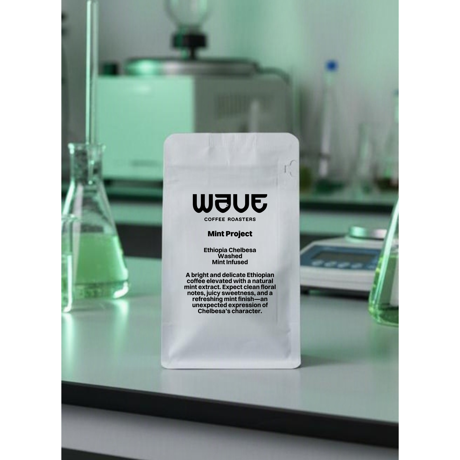 A white stand-up coffee bag with a hanging hole and a large white label reading WAVE Coffee Roasters Mint Project. Juicy Infusion method. Lab equipment